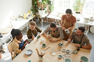 High angle shot of creative group of people decorating ceramics in pottery workshop, copy space - Powered by Adobe