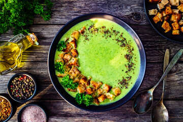 Cream zucchini soup with croutons and fresh parsley on wooden table