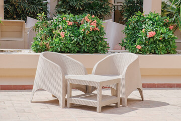 Fototapeta na wymiar Plastic wicker garden furniture set. A table and two armchairs made of wicker plastic. Lightweight portable garden furniture for a country house, terraces.