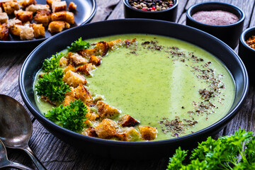 Cream zucchini soup with croutons and fresh parsley on wooden table