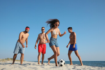 Group of friends playing football on beach