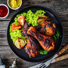 Barbecue chicken drumsticks with fresh vegetables on wooden table
