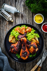 Barbecue chicken drumsticks with fresh vegetables on wooden table

