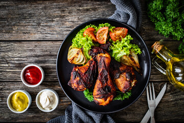 Barbecue chicken drumsticks with fresh vegetables on wooden table
