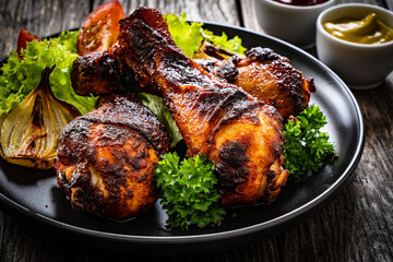 Barbecue chicken drumsticks with fresh vegetables on wooden table
