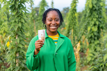 Shot of a happy female African farmer in Nigeria holding some money