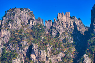 High granite mountains with green trees, blue sky and white clouds. Landscape of Mount Huangshan (Yellow Mountain). UNESCO World Heritage Site. Anhui Province, China.