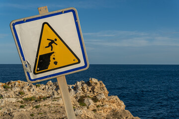 Close-up of a danger sign for people falling down a ravine, crooked. In the background the...