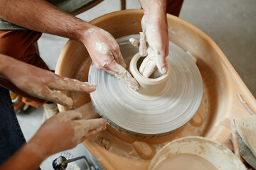 Close up young couple working on pottery wheel together in handmade ceramics workshop, copy space