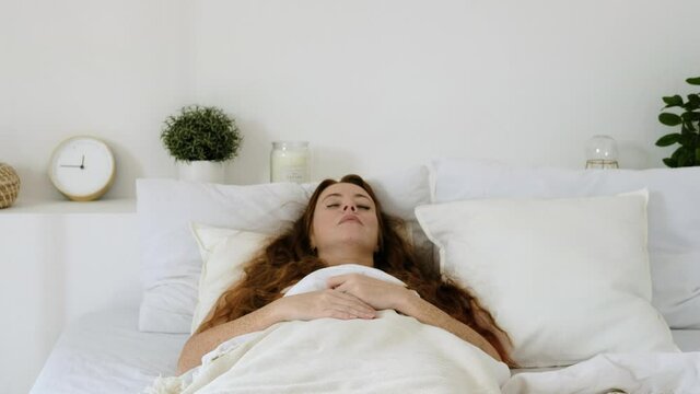 Young woman suddenly wakes up realizing that she overslept. Waking up in bedroom of room in morning. Stress after sleep. girl is sad because she overslept for work