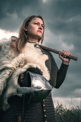 Portrait of woman in image of medieval warrior under dramatic sky. Beautiful woman in medieval...