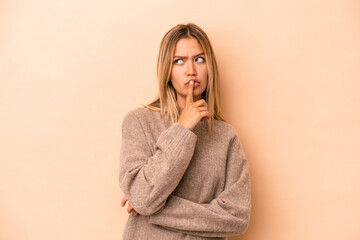 Young caucasian woman isolated on beige background keeping a secret or asking for silence.