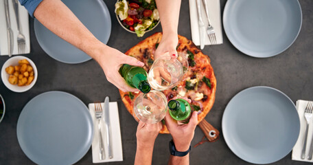 Overhead View Of Friends Making Toast Sitting Around Table In Pizza Restaurant