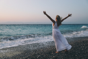 Sommer. Sonnenuntergang. Griechenland. Rhodos. Meer. Mädchen am Meer. Ein Mädchen in einem Kleid. Mädchen am Strand. Das Mädchen ruht sich aus. See Luft. Glück. Freiheit. Entspannen.