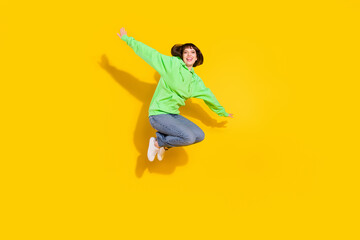 Fototapeta na wymiar Full body photo of cheerful pretty young woman jump up air hold hands wings plane isolated on yellow color background