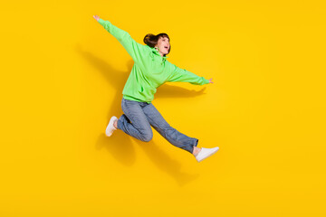 Fototapeta na wymiar Full length photo of cheerful happy young woman jump up hands wings isolated on shine yellow color background
