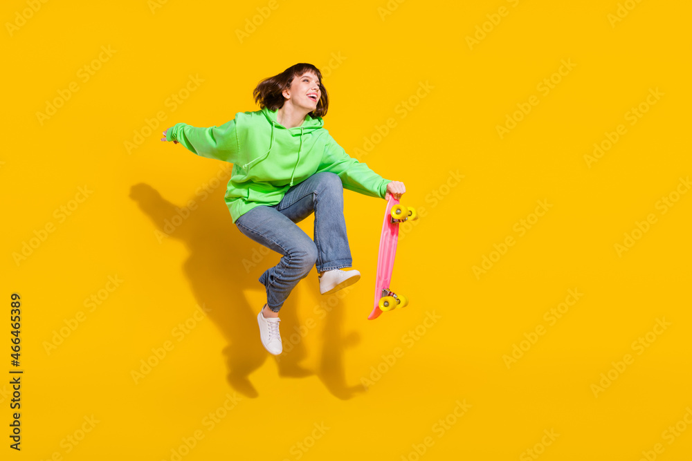 Sticker Full length body size view of pretty cheery girl jumping riding skate having fun spare time isolated over bright yellow color background