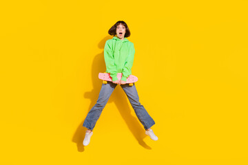 Full length body size view of pretty amazed girl jumping holding skate isolated over bright yellow color background