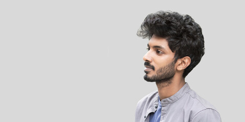 Handsome indian young man closeup portrait, profile view. Serious cheerful men isolated studio shot, panoramic banner