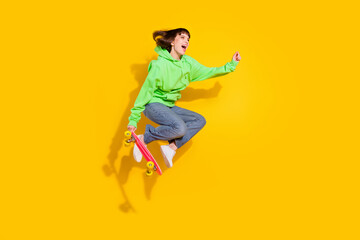 Fototapeta na wymiar Full body photo of cheerful funky young woman look empty space jump ride longboard isolated on yellow color background