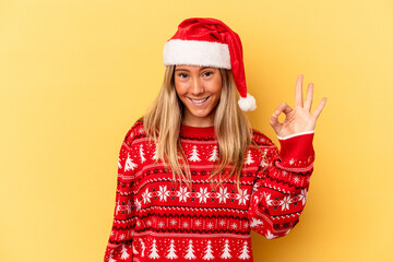 Young caucasian woman celebrating Christmas isolated on yellow background cheerful and confident showing ok gesture.