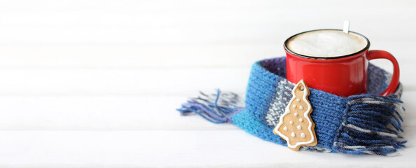baking in the shape of a Christmas tree and a red mug with frothy coffee wrapped in a knitted blue scarf. warm winter mornings