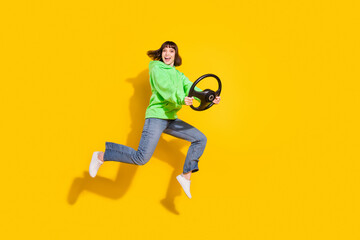 Full length body size view of nice cheery girl jumping holding steering wheel ride isolated over bright yellow color background