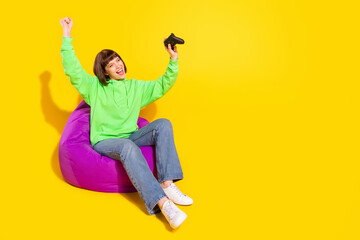 Portrait of attractive cheerful girl playing video game having fun isolated over bright yellow color background