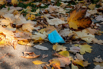 A used blue disposable medical mask was thrown to the ground.  Environmental pollution with medical masks.