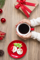 Merry Christmas with woman hand holding coffee cup and homemade cookie on table. Xmas eve, party, holiday and happy New Year concept