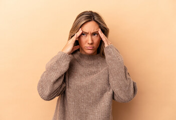 Young caucasian woman isolated on beige background touching temples and having headache.