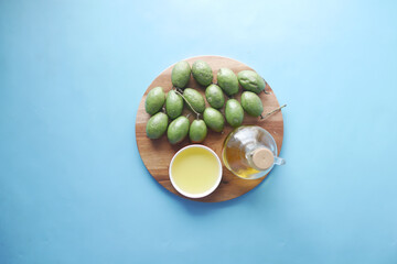 bottle of olive oil and fresh olive in a container on table .