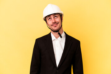 Young architect caucasian man isolated on yellow background dreaming of achieving goals and purposes