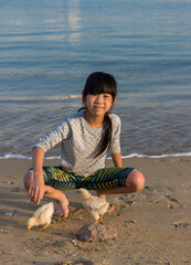 海のビーチの砂浜でヒヨコと遊んでいる子供の様子