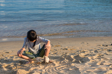 海のビーチの砂浜でヒヨコと遊んでいる子供の様子