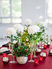 Table setting with flowers decorations and red candles. Table for celebration, catering events, wedding services, birthday banquet. Thanksgiving day, Christmas evening or wedding party decoration.