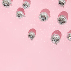 Christmas and New Year creative layout with disco ball decoration on pastel pink background. 80s or 90s aesthetic fashion holiday concept. Trendy minimal holiday idea.