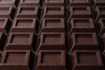 Close up a chocolate bar background. Chocolate bar cubes macro
