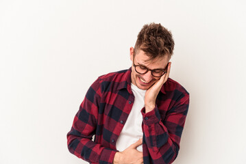 Young caucasian man isolated on white background laughs happily and has fun keeping hands on stomach.