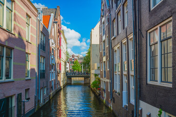 Fototapeta na wymiar Unique Amsterdam - Narrow canal of Amsterdam with old traditional houses on the water. A beautiful sunny day.