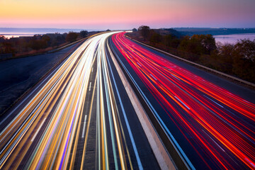 Light trails of cars on the road. Sunset time. Transport creative background. Long exposure, motion and blur.