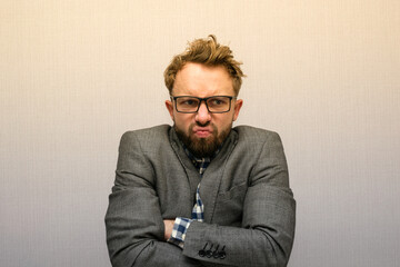 Funny nerdy weirdo caucasian bearded man with eyeglasses in a suit disappointed and mad being ...
