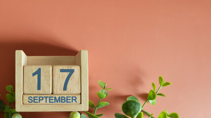 September 17, Date design with calendar cube and leaf on orange background.