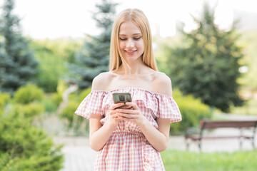 Naklejka premium Happy and attractive blonde girl holding a smartphone. Online working. Freelance