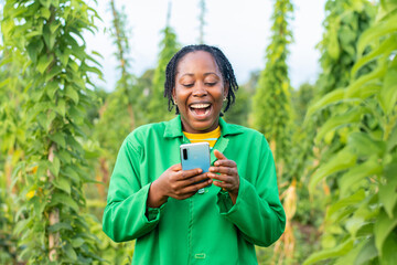 Shot of an excited female African farmer in Nigeria using her smartphone