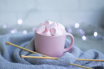 knitting needles, a cup of coffee with pink marshmallows.Christmas lights.