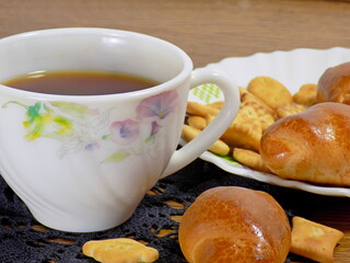 A butter bun next to a strong cup of tea.