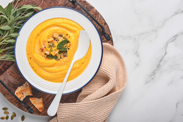 Pumpkin traditional soup with creamy silky texture with sage leaves and red pepper in white plate or bowl. Light grey background. Copy space. Mock up. Top view, flat lay.