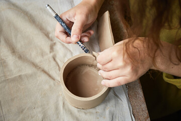 Fototapeta na wymiar Female ceramist working in pottery studio. Ceramist's Hands Dirty Of Clay. Process of creating pottery. Master ceramist works in her studio