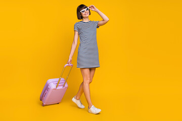Full length photo of funny brunette young lady go with bag wear dress sneakers eyewear isolated on yellow background